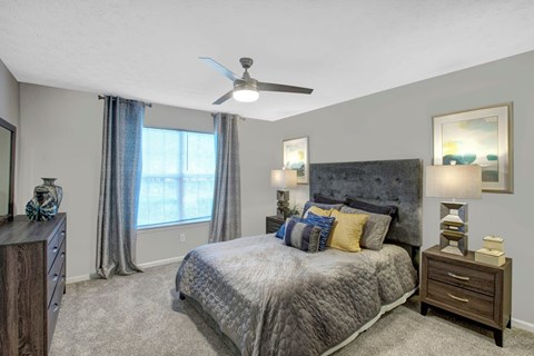 A bedroom with a large bed and a ceiling fan.