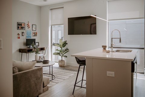 A modern living room with a white kitchen island and a flat-screen TV mounted on the wall.