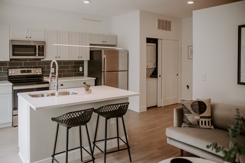 A modern kitchen with a white island and bar stools.