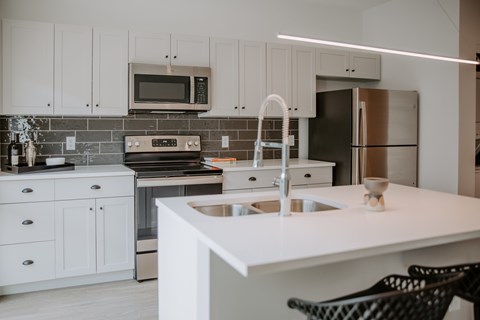 A modern kitchen with white cabinets and a white island.