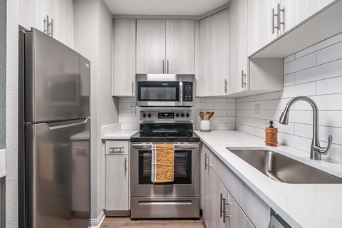A modern kitchen with a stainless steel refrigerator and a stove with an oven.