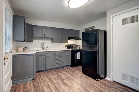 A kitchen with dark wood cabinets and a black refrigerator.