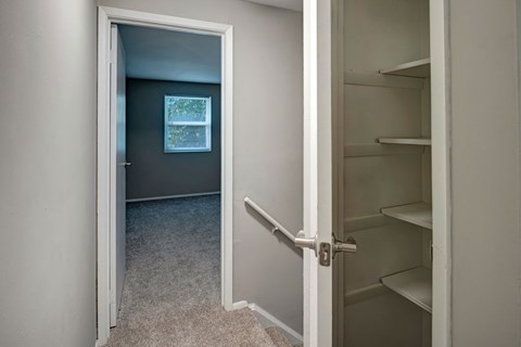 A white door is open to a room with a window and a pile of shelves.