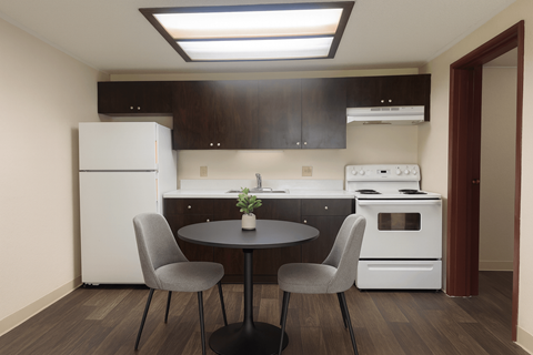 A kitchen with a table and two chairs.