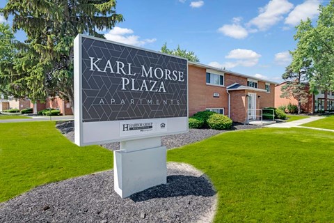 A sign for Karl Morse Plaza Apartments stands in front of apartment buildings.