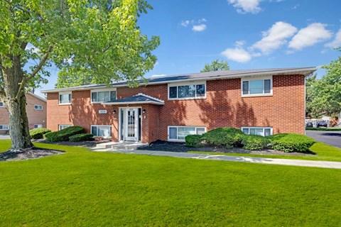 A red brick house with a tree in front.