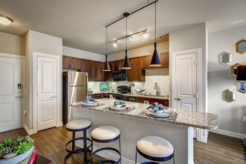 A kitchen with a granite countertop and bar stools.