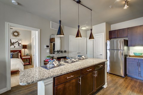 A kitchen with a marble countertop and wooden cabinets.