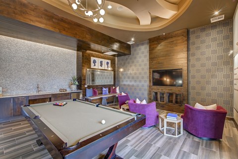 A pool table is in the middle of a room with a fireplace and a TV.