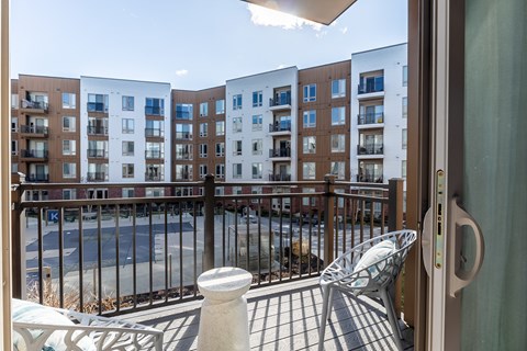 A balcony with a chair and a railing overlooking a pool.