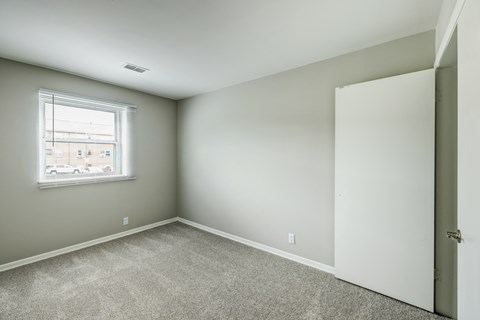 A room with a carpeted floor and a window.