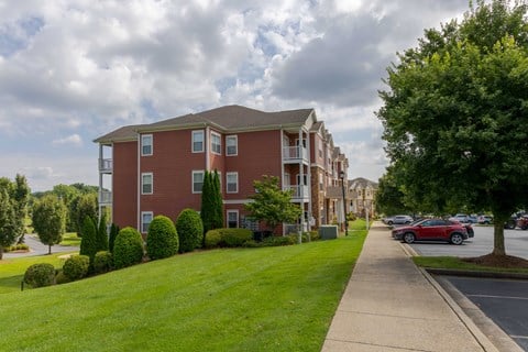 A red brick apartment building with a green lawn in front.