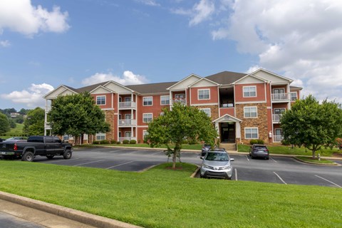 A large red brick apartment building with a parking lot in front.