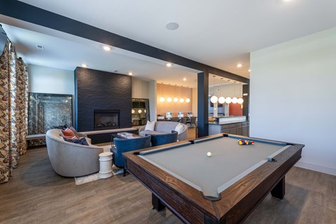 A pool table is in the middle of a room with a fireplace and a chair.
