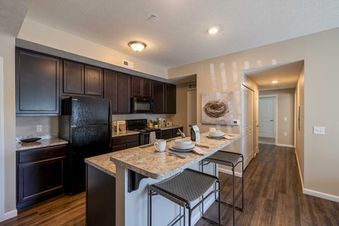A kitchen with a black refrigerator and brown cabinets.