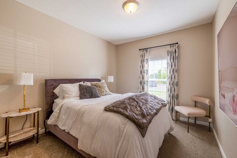 A bedroom with a large bed and a chair.