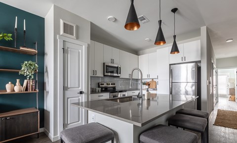 A modern kitchen with a large island and stools.