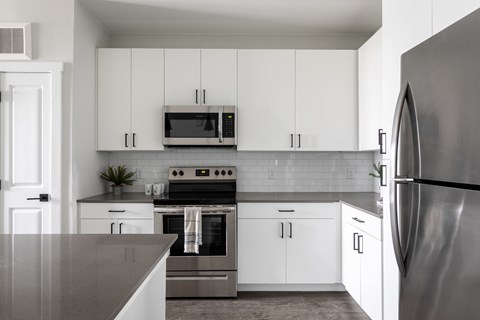 A modern kitchen with white cabinets and stainless steel appliances.