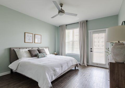 A bedroom with a bed, a ceiling fan, and a nightstand with a lamp.