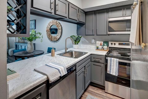 A modern kitchen with a marble countertop and stainless steel appliances.