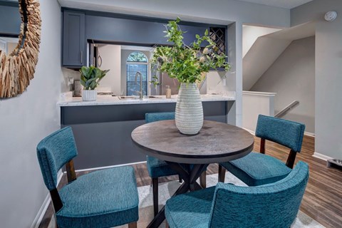 A dining room with a round table and blue chairs.