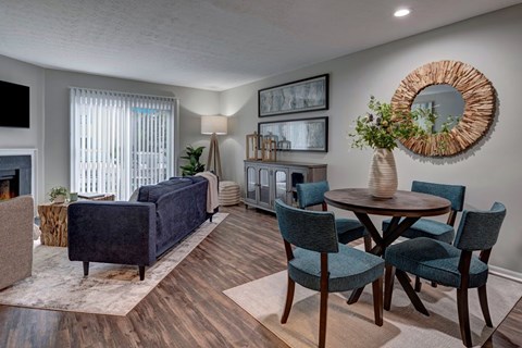 A living room with a dark blue couch, a wooden table, and a woven wall hanging.