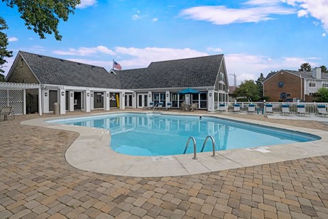 A large outdoor swimming pool surrounded by a brick patio.