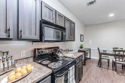 A kitchen with black cabinets and a black stove top oven.