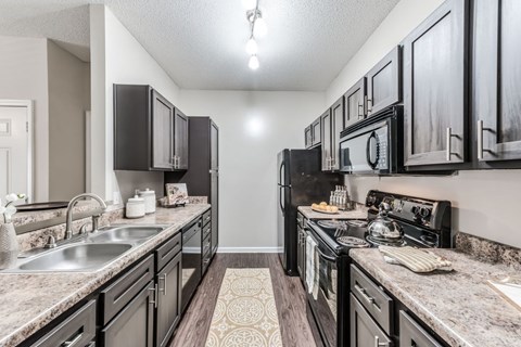 A kitchen with black cabinets and granite countertops.