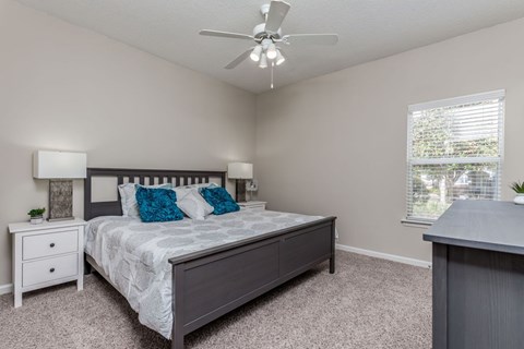A bedroom with a bed, nightstand, and window.