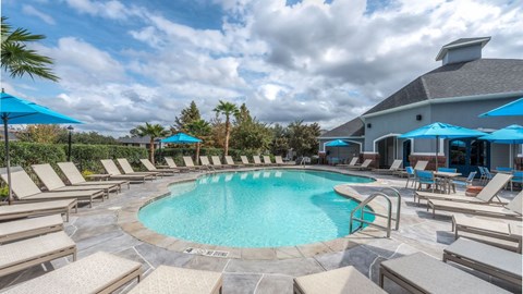 A swimming pool surrounded by lounge chairs and umbrellas.