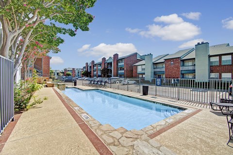 A pool surrounded by a fence and trees.
