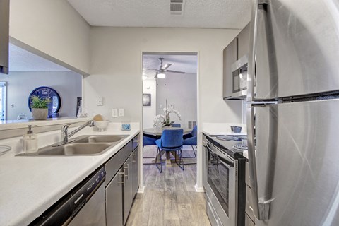 A kitchen with a refrigerator, sink, and dining table.