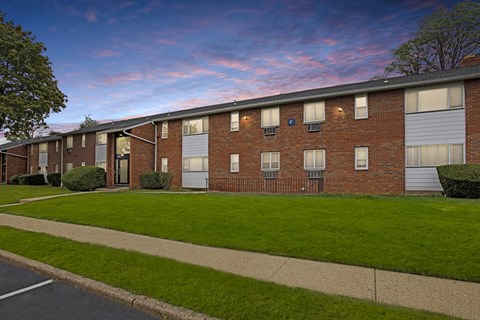 A row of red brick apartment buildings with green lawns in front.