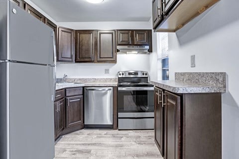A kitchen with a refrigerator, oven, and sink.