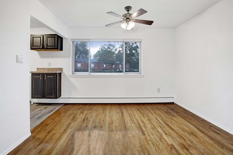 A room with a ceiling fan and a window overlooking a residential area.