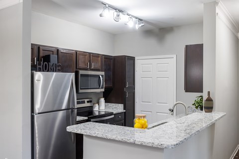 A kitchen with a granite countertop and stainless steel appliances.