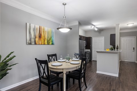 A dining room with a table set for two and a painting on the wall.
