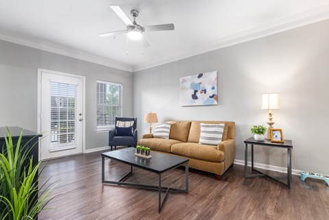 A living room with a brown couch, a black coffee table, and a ceiling fan.