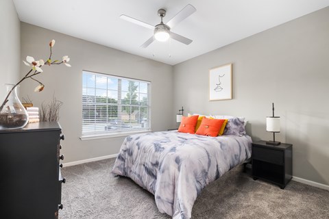 A bedroom with a bed, nightstand, and a vase with flowers.