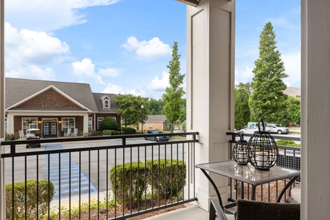 A patio with a table and chairs overlooks a pool and a house.
