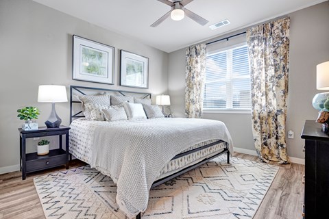 A bedroom with a large bed, a ceiling fan, and a rug on the floor.