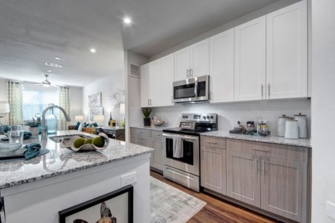 A modern kitchen with white cabinets and a marble countertop.