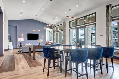 A modern dining room with a long table and blue chairs.