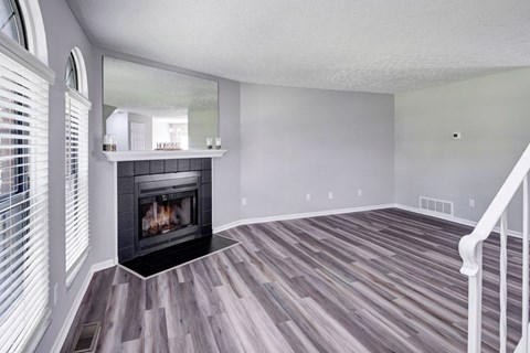 A room with a fireplace and wood flooring.
