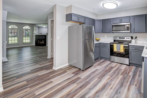 A kitchen with a refrigerator, oven, and microwave.