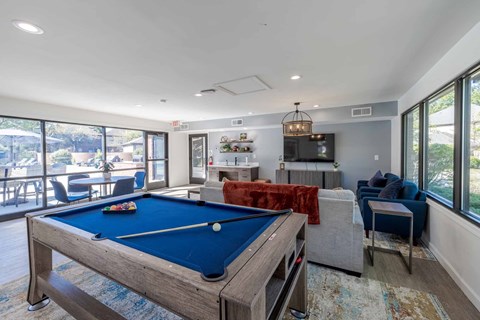 A pool table is in the middle of a living room.