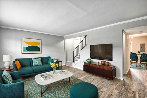 A living room with a green couch, a white coffee table, and a painting on the wall.
