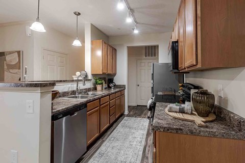 A kitchen with a granite countertop and wooden cabinets.