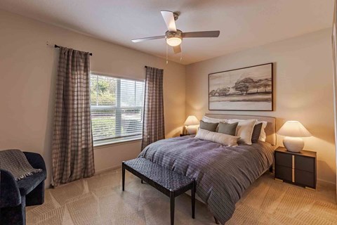 A bedroom with a bed, chair, and painting on the wall.